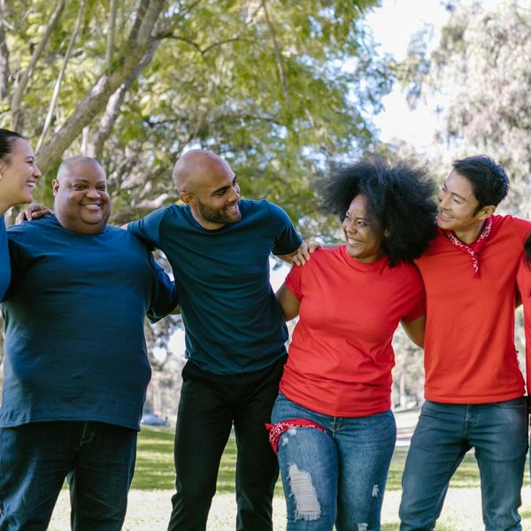 A diverse group of friends smiling after a morning run in a park.